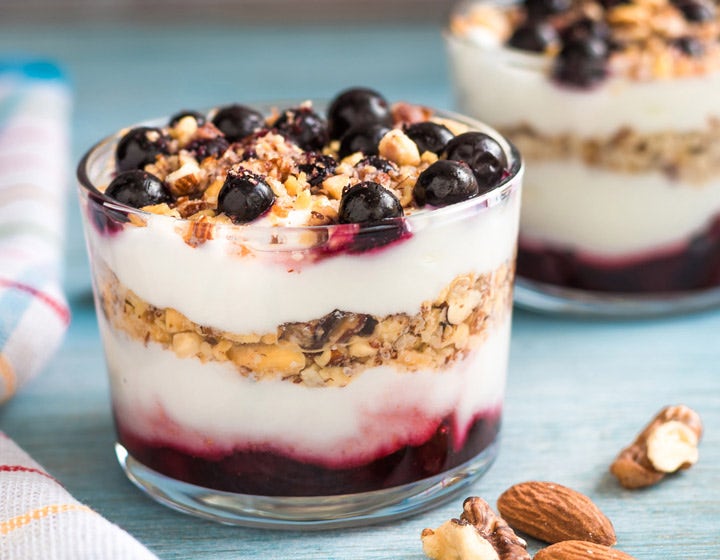 Glass of yogurt layered with granola, blueberries, and almonds, representing added nutrition
