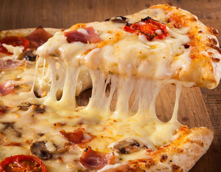 Hot pizza slice with stretchy melted cheese pulling away from the pie