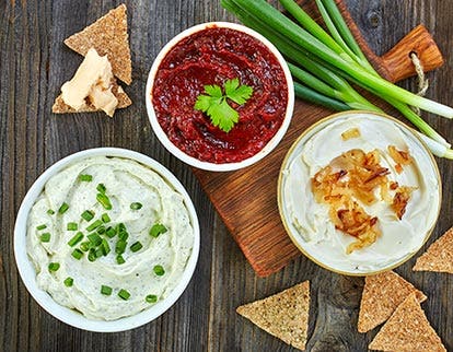 Assorted bowls of creamy white dip, red sauce, and onion dip, representing dressings and dips solutions