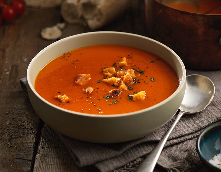 Bowl of tomato soup garnished with croutons and herbs, showcasing gluten-free savory solutions