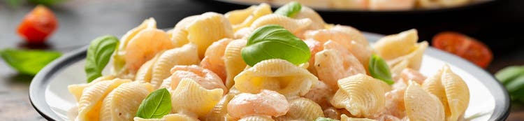 Bowl of pasta shells garnished with basil, representing ready meal ingredient solutions